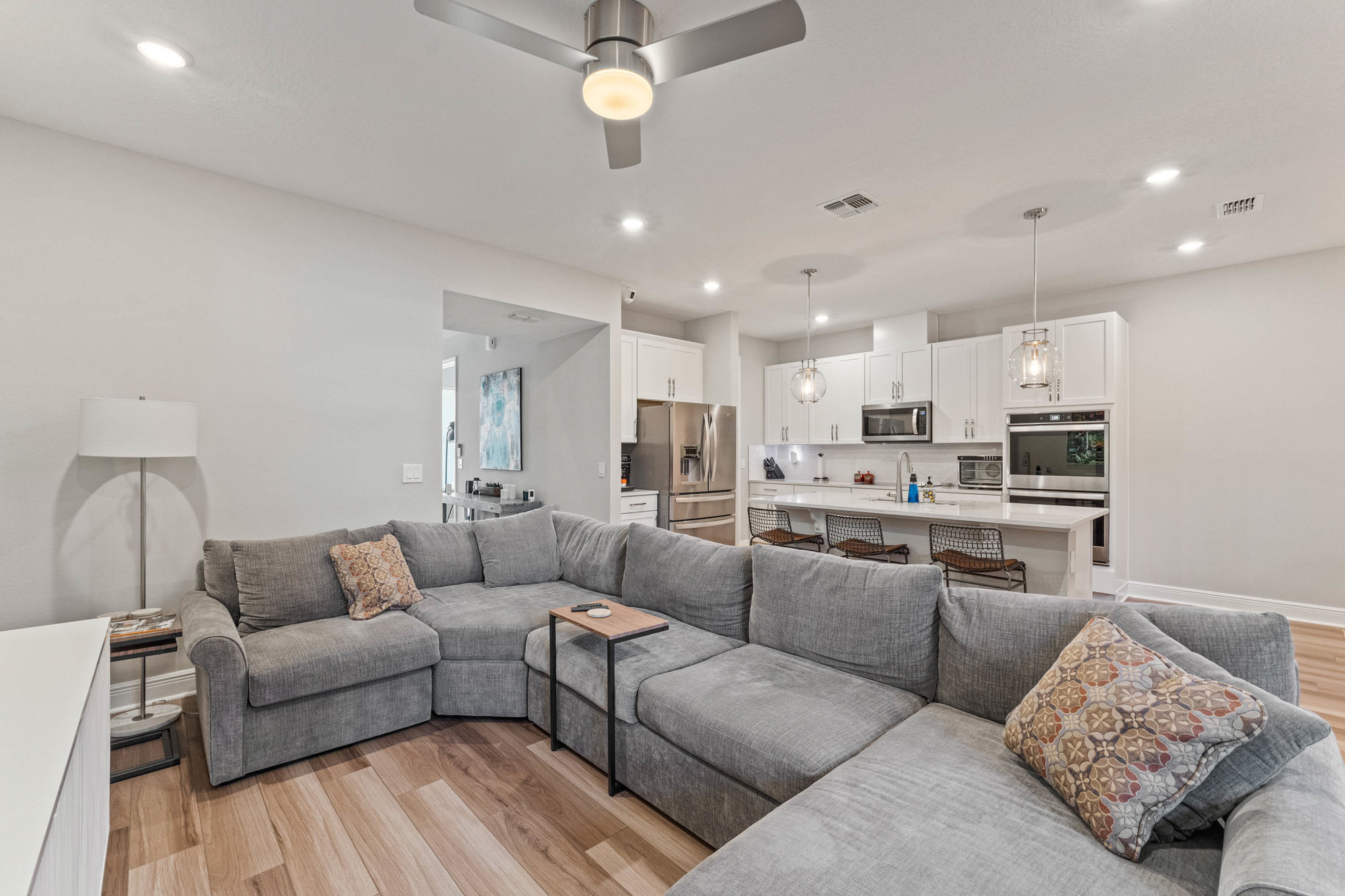 large grey sectional with kitchen in back and white walls